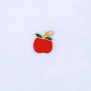Enamel apple charm detail, gold rim and green leaves, perfect for DIY jewelry and keychains.