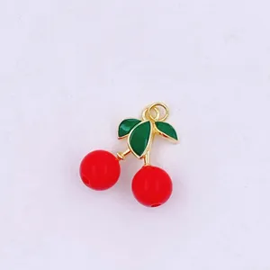 Close up view of a cute 3D cherry charm pendant with red fruit and green enamel leaves.