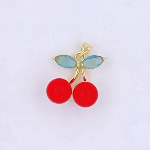 Cherry pendant detail shot, gold tone frame with red oil drop beads and blue leaf stones.