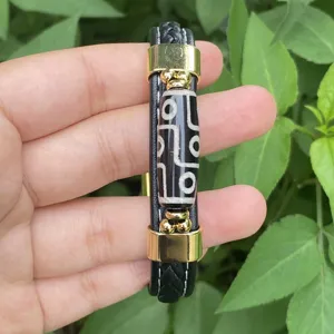 Detailed shot of men leather braided bracelet with tribal dzi bead and gold metal accents.
