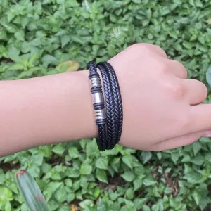 Nahaufnahme eines mehrschichtigen schwarzen geflochtenen Lederarmbands mit Metallröhren.