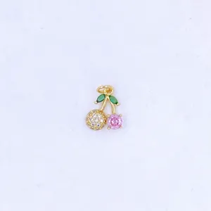 Detailed shot of a gold cherry pendant featuring micro-set white and pink cubic zirconia.