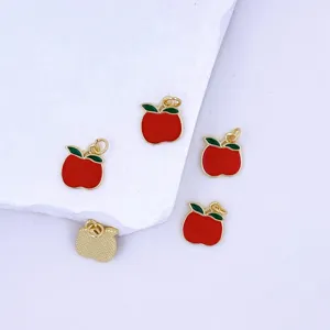 Close-up detail of red apple enamel charms, cute metal pendant accessories for DIY jewelry making.