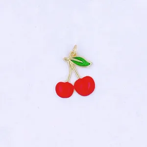 Primo piano dettagliato di un grazioso ciondolo a ciliegia 3D, rame dorato con smalto rosso e verde.