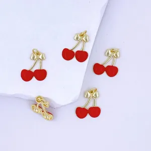 Detail view of red cherry enamel pendants with gold trim for DIY jewelry crafting.