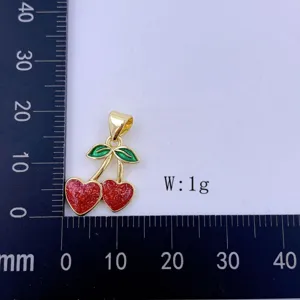 Vergoldeter Doppelherz-Kirschen-Anhänger mit glitzerndem rotem Emaill und grünen Blättern.