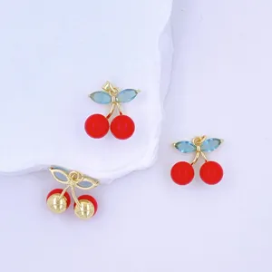 Close-up of DIY cherry pendant jewelry charms featuring red enamel beads and crystal leaves.