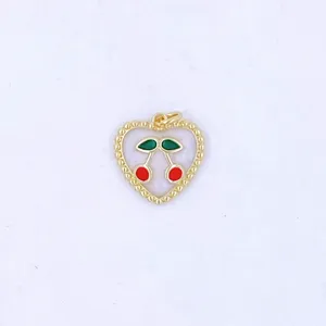 Close up of a sweet heart shaped cherry pendant with enamel red and green details and gold bead trim.