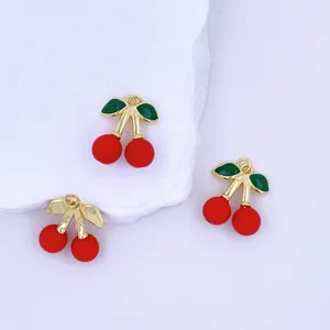 Close-up of DIY cherry pendants featuring glossy red fruit, gold stems, and green leaves.