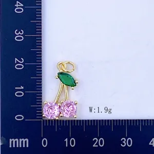 Close up detail view of the gold cherry pendant with pink and green cubic zirconia stones.