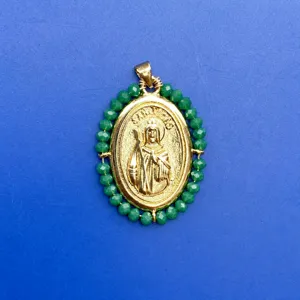 Gros plan d'un pendentif ovale plaqué or avec une bordure de perles en acrylique vert.