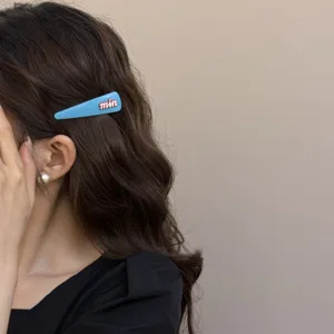 Close-up detail van een stijlvolle blauwe haarspeld in donker golvend haar, chique accessoire.