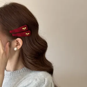 Gedetailleerde close-up van rode fluwelen haarspelden met een elegante gouden strik.