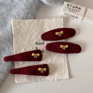 Gedetailleerd overzicht van rode fluwelen haarspeld met gouden strik voor mooie vrouwen.