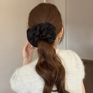 Detailopname van een chic zwarte haarscrunchie met volants in een paardenstaart.
