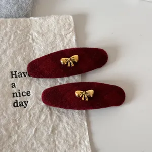 Detailopname van elegante rode fluwelen haarspelden met gouden strikjes voor dagelijks gebruik.