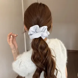 Detailed shot of a light blue satin hair scrunchie showing soft fabric and fluffy texture.