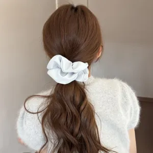 Elegant light blue satin hair scrunchie detail shot, soft fabric ponytail holder accessory.
