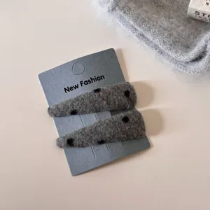 Gedetailleerd overzicht van de pluizige grijze stippen haarspeld met zachte textuur.