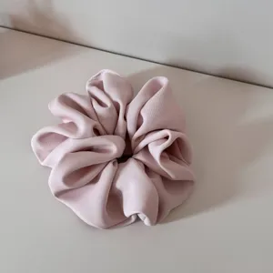 Detailed shot of a stylish pink fabric hair scrunchie, soft texture and chic pleated design.