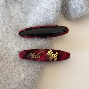 Détail de pince à cheveux à motif écossais rouge avec charmant chien doré et design unique.