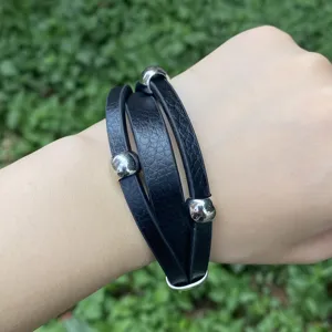 Nahaufnahme Detail eines mehrschichtigen schwarzen Lederarmbands mit Metallkugeln.