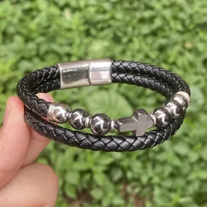 Nahaufnahme des schwarzen geflochtenen Lederarmbands mit einem Edelstahlkreuz und Verschluss.