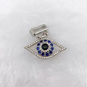 Close-up of evil eye pendant detail, sparkling blue and clear stones, silver tone DIY charm.
