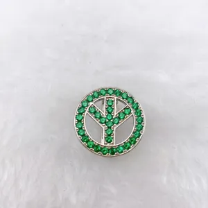 Close-up detail of silver peace symbol charm with green gems for DIY jewelry making.