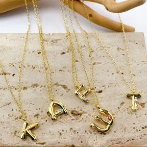 Close-up of 18K gold plated letter pendant necklaces with colorful evil eye details.