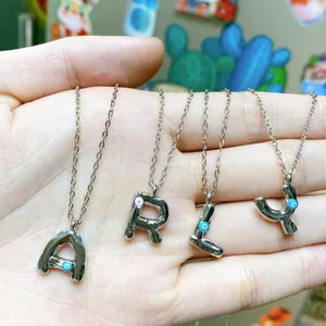 Detail view of silver letter necklaces A R L Y with evil eye charms, fashion metal jewelry detail.