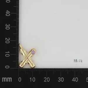 Close-up of gold-plated X letter pendant with purple evil eye detail, measurement view.