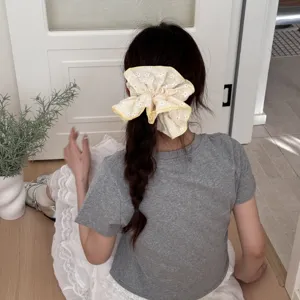 Vue détail chouchou imprimé fleurs jaunes, montrant le design d'accessoire cheveux en tissu.