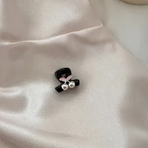 Exquisite detail of a cute black hair claw featuring a pink bow and shiny silver beads.