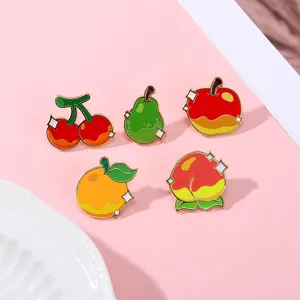 Close-up detail of cute fruit enamel pins featuring colorful cherry, pear, apple and peach designs.
