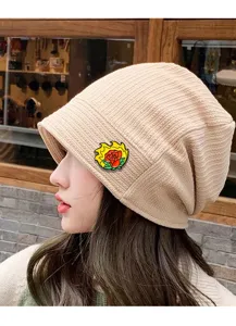 Stylish vintage beige knitted beanie hat paired with a vibrant flaming rose enamel brooch.