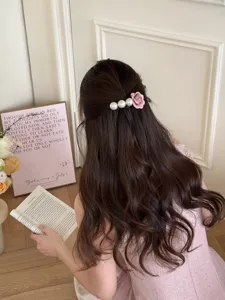 Detail view of a French style hair comb decorated with faux pearls and pink fabric flower.
