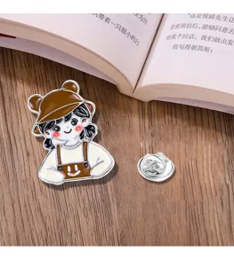 Cute cartoon girl enamel brooch metal lapel pin badge detailed close-up shot on table.