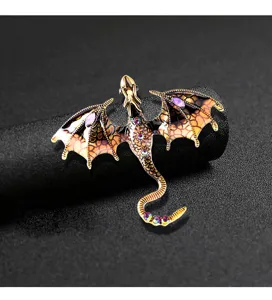 Close-up detail of vintage gothic dragon brooch featuring colorful crystals and wings.
