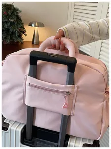 Detailweergave van de roze reistas met een handige kofferriem voor comfortabel reizen.