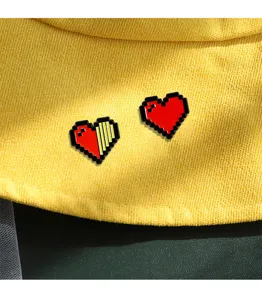 Close-up detail of cute pixel heart enamel brooch pins, vibrant retro gaming style design.