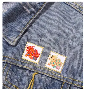 Primer plano detalle de pines de solapa esmaltados de dragon chino sobre tela de denim.