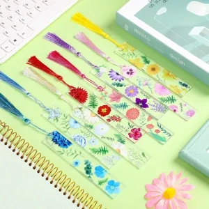 Detalle de marcapáginas de acrílico transparente con estampado floral y borla de color elegante.
