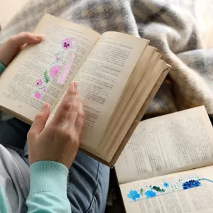 Detalle de marcapáginas de acrílico con estampado floral y borla en escena de lectura