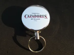 Llavero retráctil de metal con anilla y diseño de logotipo de marca impreso en superficie.