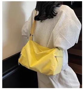 Detail shot of a casual yellow travel duffel bag worn by a model, showing large capacity.