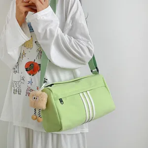 Detail view of light green casual canvas crossbody bag with stripes and plush charm for travel