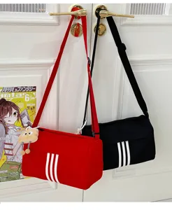 Detailed shot of casual canvas messenger bag with three stripes design hanging on door.