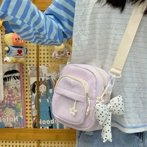 Detail view of a light purple Japanese canvas crossbody bag with star zipper and cute bow pendant.