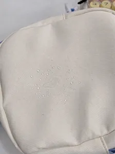 Close-up detail of water-resistant fabric material showing water droplets on small bag.